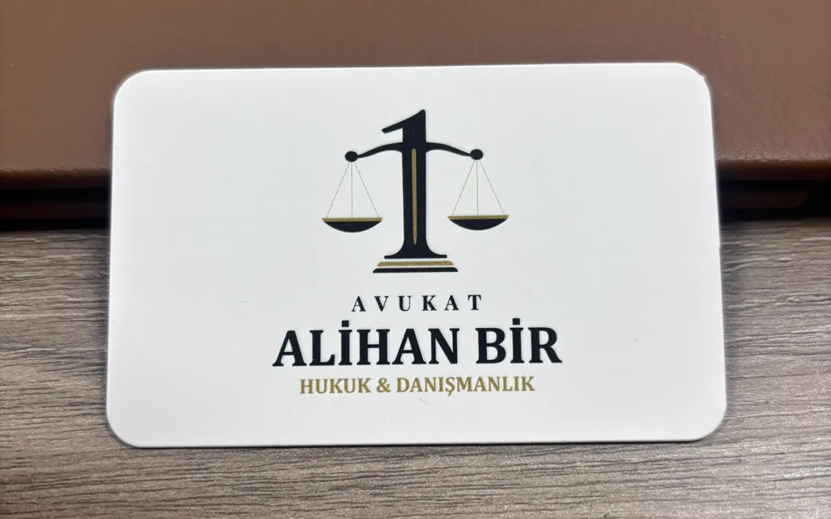 Av. Alihan Bir kartvizitinin basılı hâli, ahşap masa üzerinde ön yüz