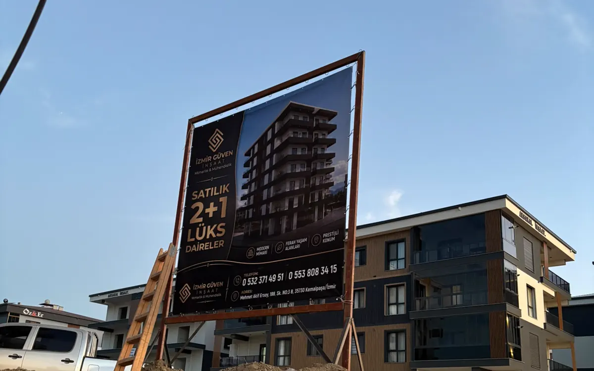 İzmir Güven İnşaat şantiye brandası, ahşap ayak üzerinde sahada asılı