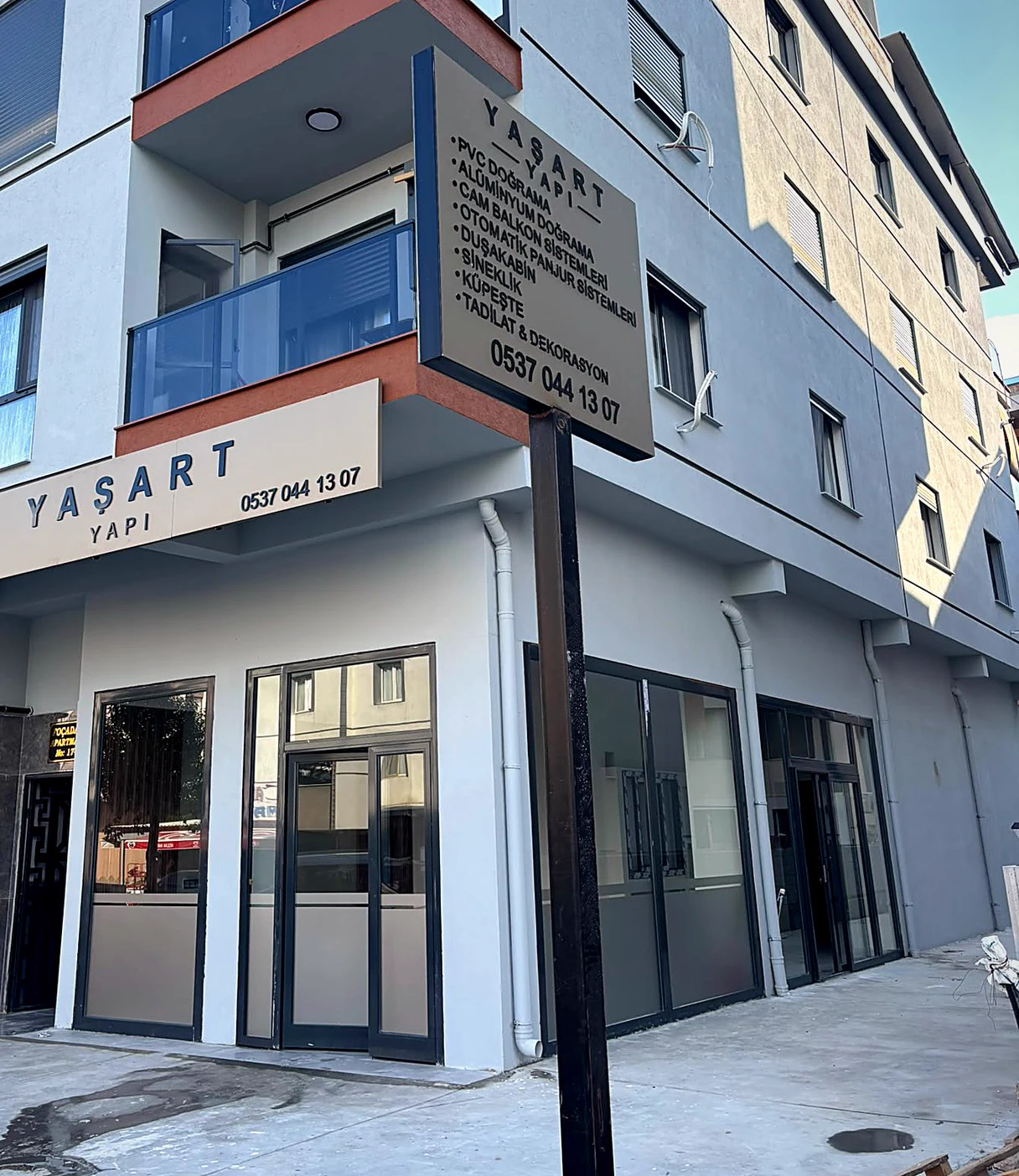 YAŞART YAPI dükkânının köşesi, cephede kutu harf tabela ve hizmet listeli totem, YAŞART YAPI, Kemalpaşa / İzmir